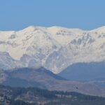 Paesaggio montano con un caratteristico villaggio e piatti tipici locali in evidenza.
