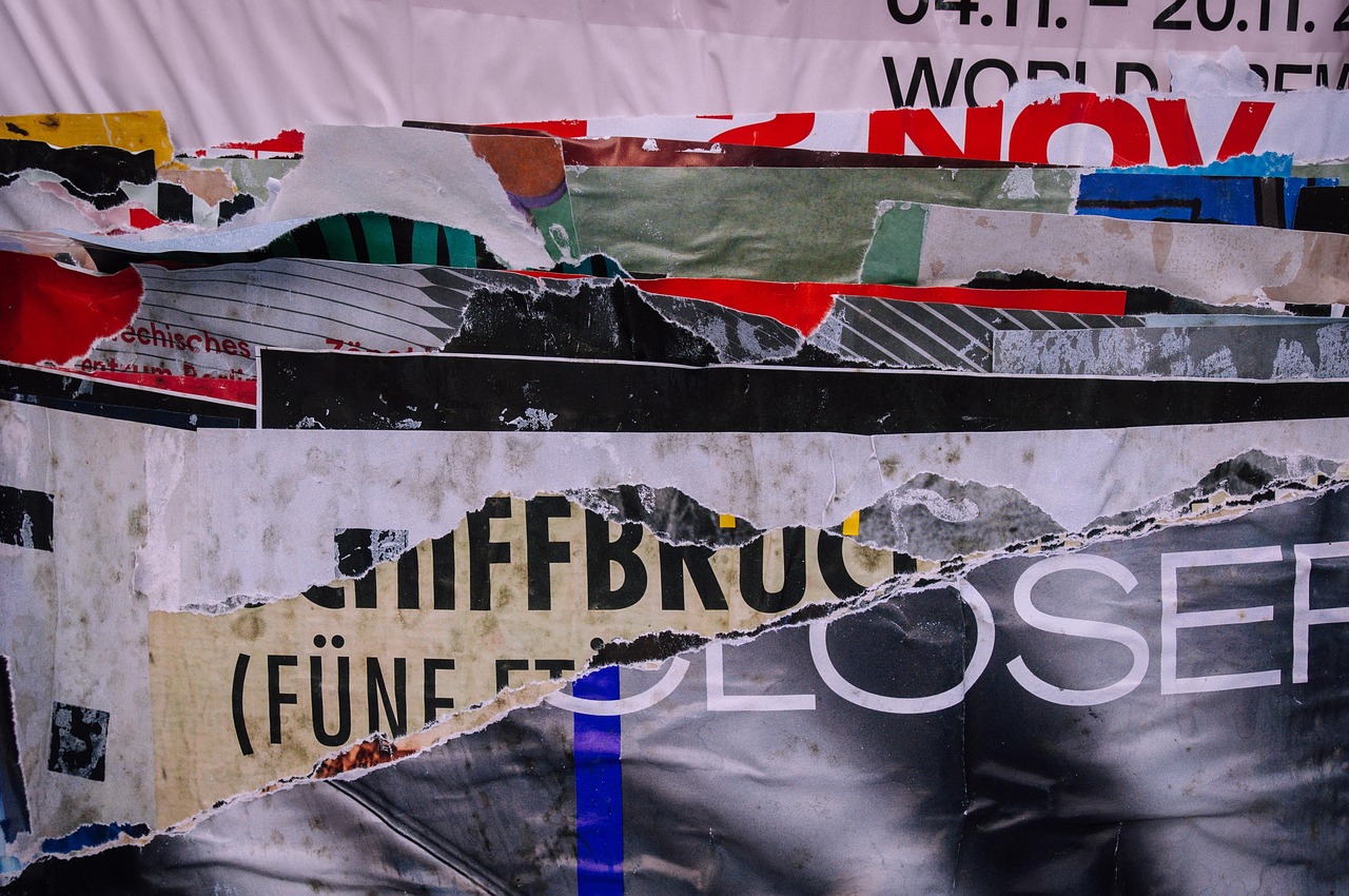 Collezione di vecchi manifesti pubblicitari esposti su una parete, evidenziando il fascino del collezionismo cartaceo.