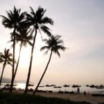 Spiaggia con sabbia dorata e mare cristallino al sorgere del sole.