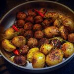 Patate croccanti in padella, con acqua fredda sullo sfondo e spezie pronte per la cottura.